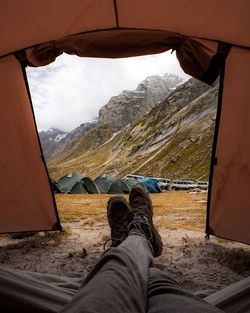 Low section of man relaxing in tent against mountains