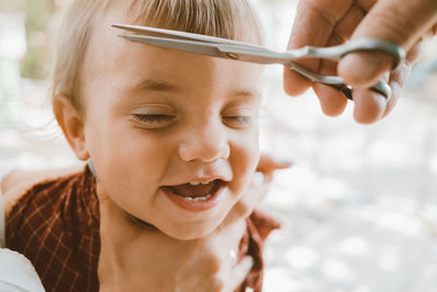 Cropped hands of hairdresser cutting boys hair outdoors