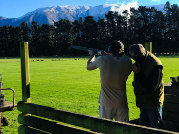 Rear view of man clay shooting against mountain