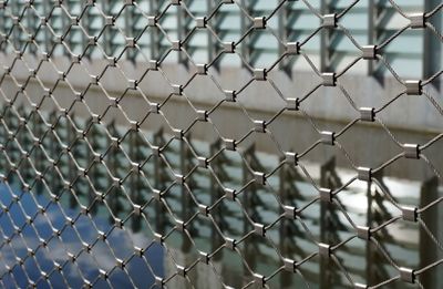 Reflection of a building in water, seen through a fence.