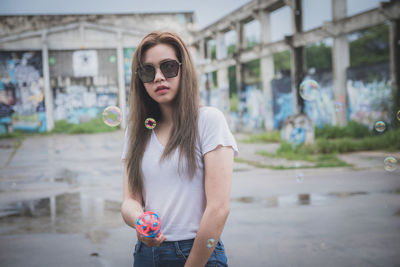 Portrait of young woman wearing sunglasses standing outdoors