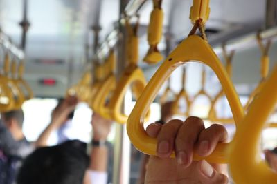 Close-up of hand holding handle hanging in train