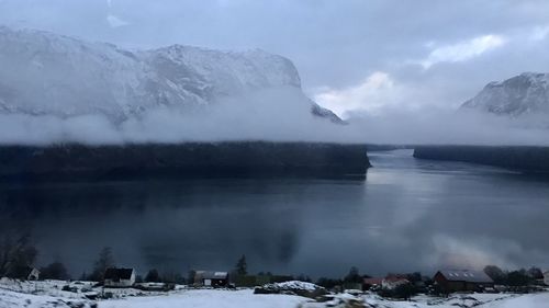 Scenic view of lake by snowcapped mountains against sky