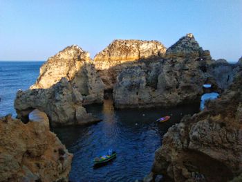 Rock formations in sea against clear sky