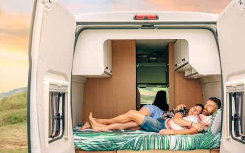 Couple sleeping embraced in the bed of their camper van with legs intertwined