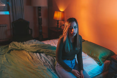 Young woman sitting on bed at home