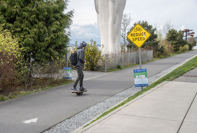 Man riding sign on road against trees