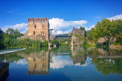 Historical building by lake against sky