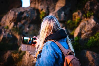 Rear view of woman taking selfie through smart phone