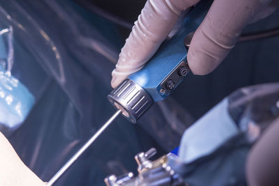 Cropped hands of doctor performing operation on patient knee in hospital