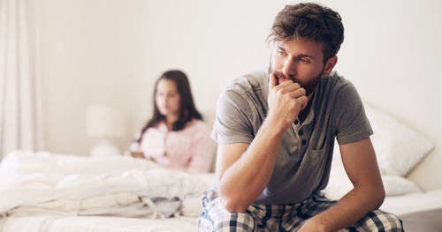 Sad man sitting on bed at home