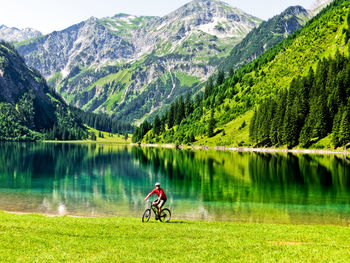 Man riding bicycle by lake