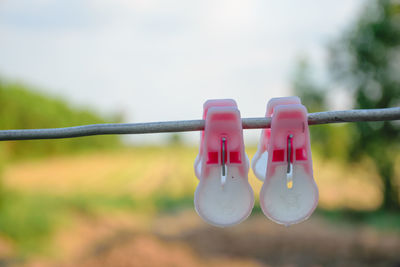 Close-up of clothespins hanging on clothesline against sky