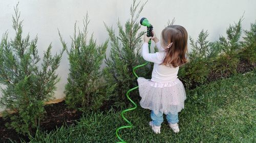 Rear view of girl watering plants