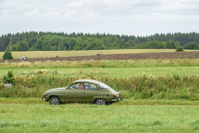 Car parked on field against sky