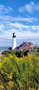 Lighthouse by sea against sky