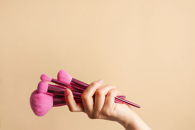 Cropped hand of woman holding gift against pink background