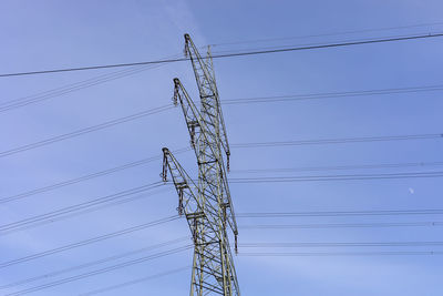 Low angle view of electricity pylon against clear blue sky