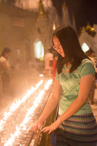 Woman burning diya at temple