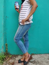 Low section of woman standing against blue wall