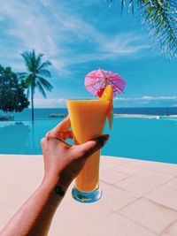 Hand holding drink at swimming pool