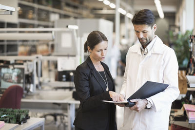 Businesswoman and engineer discussing over file in industry