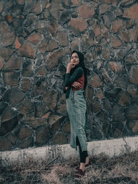 Portrait of smiling young woman standing against wall