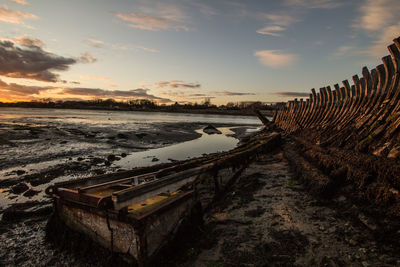 Old ruins of boat at beach during sunset