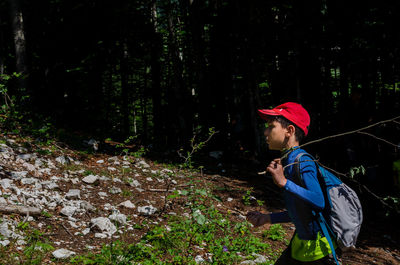 Side view of boy holding stick at forest