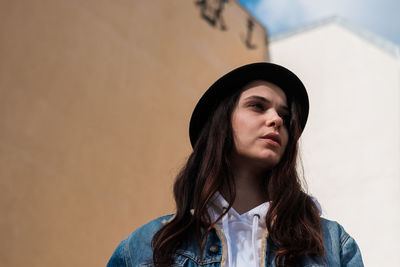 Low angle view of young woman against building