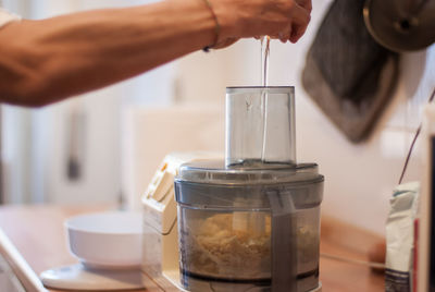 Cropped image of person pouring egg in kitchen robot