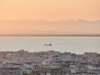 Scenic view of sea by buildings against sky during sunset