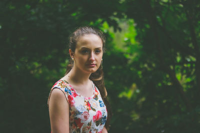 Portrait of young woman standing against tree