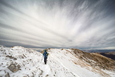 Rear view of woman on snowcapped mountain against sky