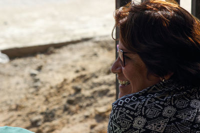 Side view of smiling mature woman at beach during sunny day
