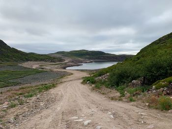 Dirt road along landscape against sky
