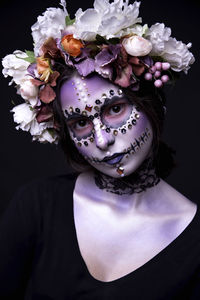 Close-up of portrait of woman with painted face against black background