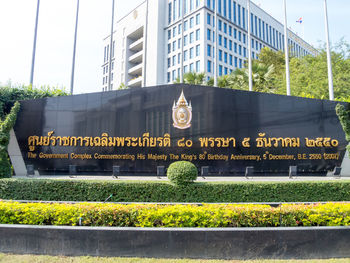 Information sign by building in city against sky