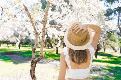 Rear view of woman wearing hat standing on field