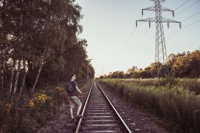 Young man with backpack standing on railroad track