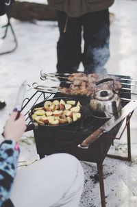Cropped image of woman preparing food on barbeque grill