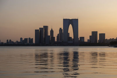 Sea by modern buildings against sky during sunset  suzhou center, landmark building, skyline
