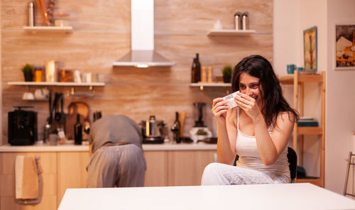 Portrait of young woman drinking coffee at home