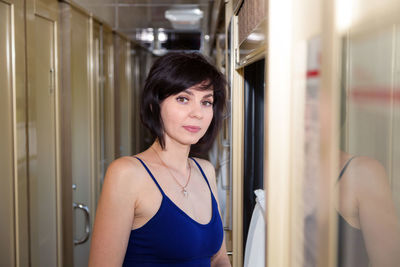 Portrait of a beautiful brunette in a blue top in the corridor of a train car going on vacation.