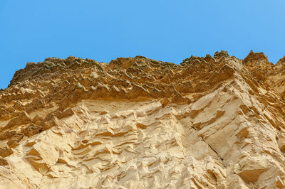 Low angle view of rock formations in desert against clear blue sky