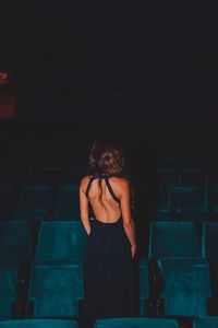 Rear view of woman wearing backless dress while standing by seats