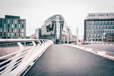 Elevated road leading towards modern buildings in city against sky