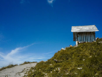 Built structure on land by trees against blue sky