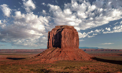 Rock formation in desert against cloudy sky