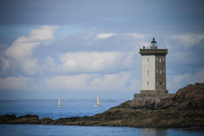 Lighthouse by sea against sky